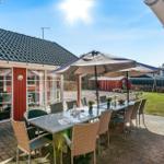 Terrace with table, chairs, and umbrella. In the background, garden and playground.