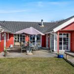 Red garden house with terrace, table, chairs, and umbrella.