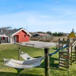 Red wooden house with garden, hammock, and playground. Outdoor table and grilling area.