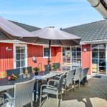 Red wooden structure with terrace, table, chairs, and umbrellas.