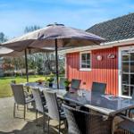 Red wooden house with terrace, dining table, and umbrella. Playground in the backyard.