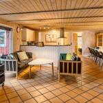 Living area with sofa, armchairs, and TV. Kitchen and dining area are visible.