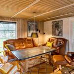 Living room with brown leather furniture, wood walls, and glass door.