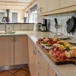 Kitchen with fruit, cheese, bread, and wine on wooden board.