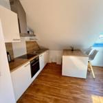 Küche mit Holzboden, Arbeitsplatte und Essbereich unter Dachschrägen.