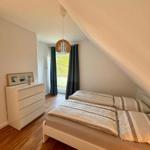 Schlafzimmer mit Dachschräge, Bett, Kleiderschrank und Fenster mit Blick.