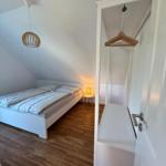 Schlafzimmer mit Dachschrägen, Bett, Kleiderschrank und Lampe.