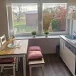 Küche mit Essbereich, Fenster mit Blick auf Garten und kleine Pflanzen auf Fensterbank.
