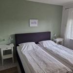 Zimmer mit Doppelbett, zwei Nachttischen und Fenster mit Blick auf Garten.