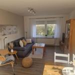 Wohnzimmer mit Sofa, Tisch, Stuhl und Fenster. Holzmöbel und Wandbild.