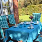 Terrasse mit gedecktem Tisch und Stühlen. Hintergrund: grüner Rasen und Hecke.