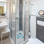 Badezimmer mit Dusche, Waschbecken und Toilette.