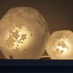 Zwei beleuchtete Lampen mit Blumenmustern auf einer Oberfläche.