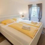 Schlafzimmer mit Doppelbett, Fenster und Nachttischen.