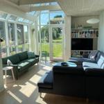 Wohnbereich mit Sofa, Fernseher und großem Fenster zur Gartenansicht.