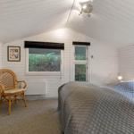 Schlafzimmer mit Bett, Stuhl und Fenstern. Weiße Wände und Decke.