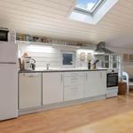 Küche mit weißer Einbauküche, Kühlschrank, Spülmaschine und Fenster.