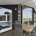 Terrasse mit Tisch, Stühlen und Grill. Schwarze Fassade und große Fenster.