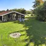 Ein Haus mit Terrasse, Garten und Liegestühlen unter Bäumen.