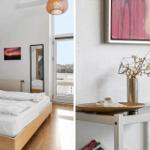 Bedroom with bed, window, and wall decor. Table with vases and artwork.