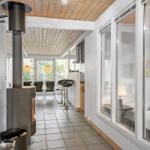 Apartment with wooden ceiling, wood stove, kitchen area, and bedroom with window.