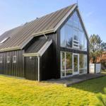 Modern wooden house with large glass area and lawn.
