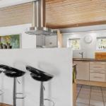 Kitchen with dining area, wooden ceiling, and black bar stools.