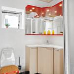 Bathroom with sink, mirror, and toilet. Red ceiling and wooden cabinets.
