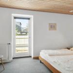 Bedroom with bed, door to balcony, and wooden ceiling.