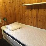 Ein Schlafzimmer mit Holzwand, Bett und Fenster.