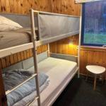 Doppelstockbett mit Matratzen und Fenster im Holzhaus.