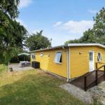 Gelbes Ferienhaus mit Terrasse und Garten unter Bäumen.