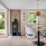 Esszimmer mit Esstisch, Stühlen und Kaminofen. Durchgang zur Terrasse mit Garten.