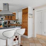 Küche mit Insel, Holzschränken und moderner Dunstabzugshaube.