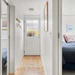 Flur mit Holzboden und Tür zu Schlafzimmer mit Bett und Wandbild