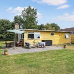 Gelbes Haus mit Terrasse, Garten und Sitzgelegenheiten unter Sonnenschutz.