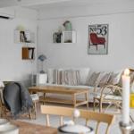 Wohnzimmer mit Sofa, Couchtisch und Stühlen. Wandregale und Poster an der Wand.
