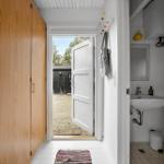 Hausgang mit Holzschrank, offener Tür zum Garten und Bad mit Waschbecken.