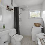 Badezimmer mit Dusche, Toilette, Waschbecken und Waschmaschine.