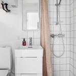 Badezimmer mit Dusche, Waschbecken und Toilette. Weiße Fliesen und rosa Streifentuch.