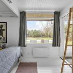 Schlafzimmer mit Bett, Fenster und Holzregal. Blick auf Garten.
