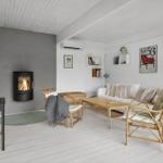 Wohnraum mit Kamin, Sofa und Stühlen. Weiße Wände und Holzboden.