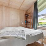 Schlafzimmer mit Holzwand, Bett, Bücherregal und Fenster mit Blick.