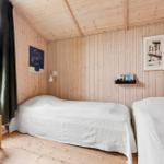 Zwei Betten in einem Holzhauszimmer mit Fenster und Stuhl.
