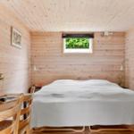 Schlafzimmer mit Holzwand, Bett, Tisch und Fenster.