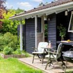 Hütte mit Terrasse, Grill und Garten. Holzterrasse mit Stühlen und Tisch.