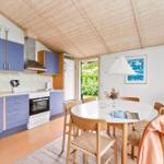 Küche mit Essbereich unter Holzdecke, blau lackierte Schränke und runde Tischplatte.