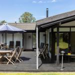 Terrasse mit Tisch, Stühlen und Sonnenschirm. Sicht auf Wohnbereich und Garten.