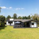 Ein Haus mit Terrasse, Garten und Sonnenschirm unter blauem Himmel.