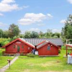 Roter Holzhauskomplex mit Garten und Fahrradabstellplatz unter blauem Himmel.